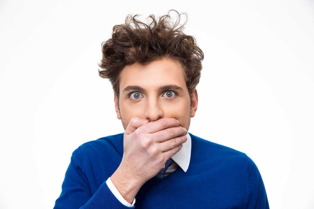 Portrait of a young man covering his mouth over white background
