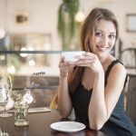 Portrait of happy young woman having coffee at restaurant